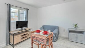 A modern living room with a TV, dining table, and a covered sofa. - Cozy Lompoc Studio w/ Patio ~ 9 Mi to Beach (Lompoc)