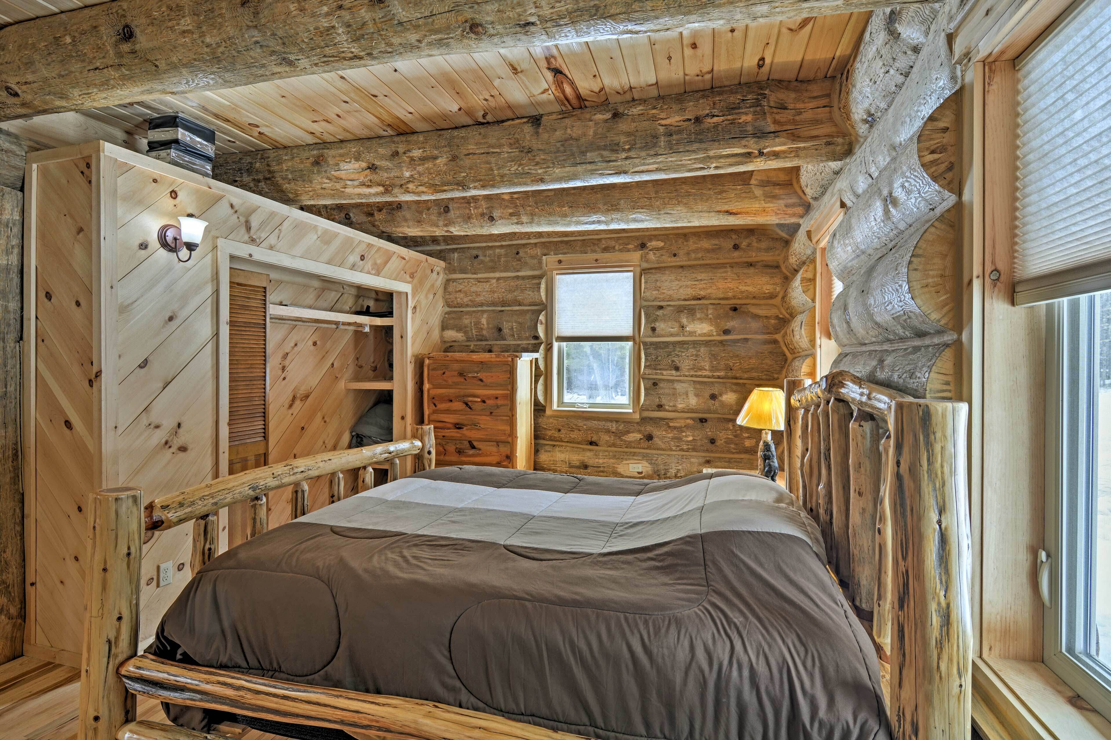 Un dormitori de cabana amb llit, finestra i armari de fusta.