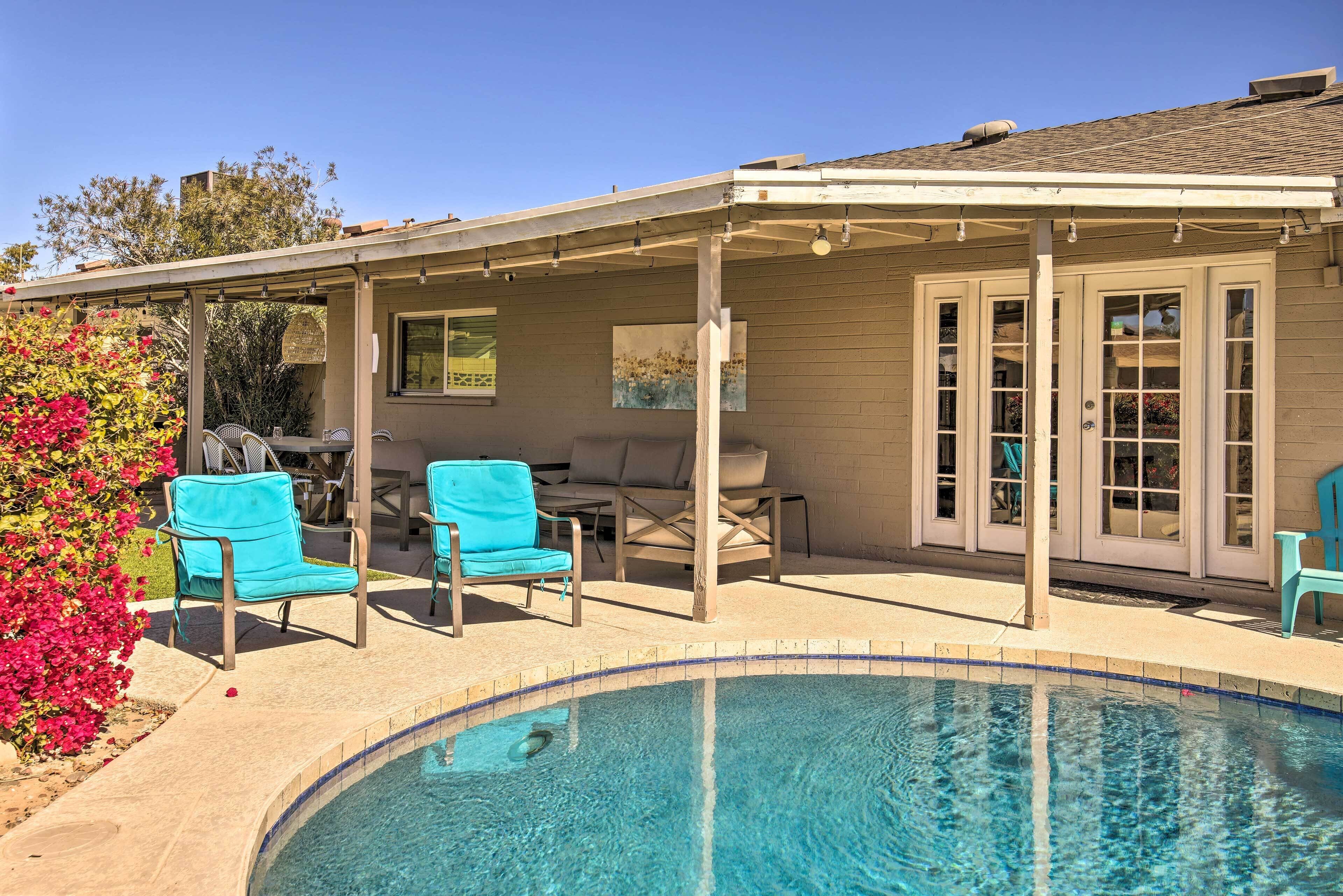A covered outdoor area with a pool, chairs, and a patio table.