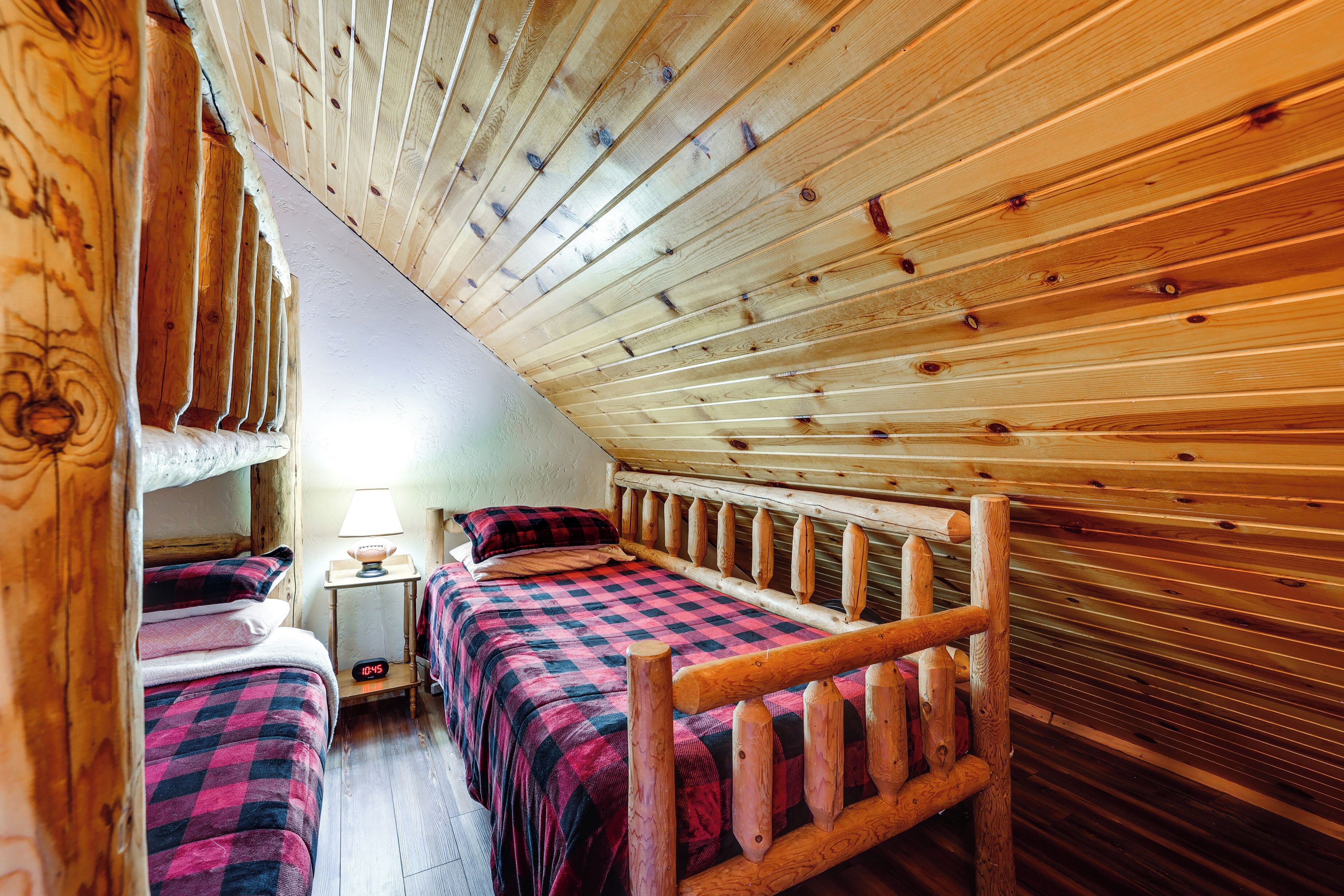 Una habitación acogedora con techo inclinado, paredes de madera y dos camas con ropa de cama a cuadros.