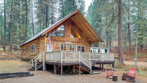 A log cabin with a porch, a staircase, and a flag. - Peaceful Garden Valley Cabin w/ Private Deck! (Garden Valley)