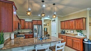 A kitchen with granite countertops, wooden cabinets, stainless steel appliances, and pendant lighting. - Game Room, Fenced Yard: Estrella Oasis in Goodyear (Goodyear)