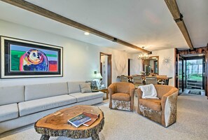 A modern living room with a sofa, two armchairs, a coffee table, and a dining area in the background.