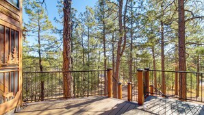 A wooden deck with a metal railing, surrounded by tall pine trees. - Hot Tub: 'ponderosa Paradise' Overgaard Cabin (Overgaard)