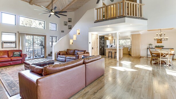 A spacious living area with a large leather sofa, a dining table, and a kitchen in the background. - Hot Tub: 'ponderosa Paradise' Overgaard Cabin (Overgaard)
