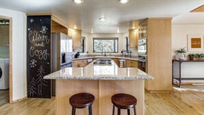A modern kitchen with a central island, wooden cabinets, and a chalkboard with holiday decorations. - Hot Tub: 'ponderosa Paradise' Overgaard Cabin (Overgaard)
