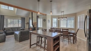 Ein geräumiges Wohnzimmer mit großem Holzesstisch, dunkelbraunen Ledersofas und einer Küchenzeile inklusive Kühlschrank.