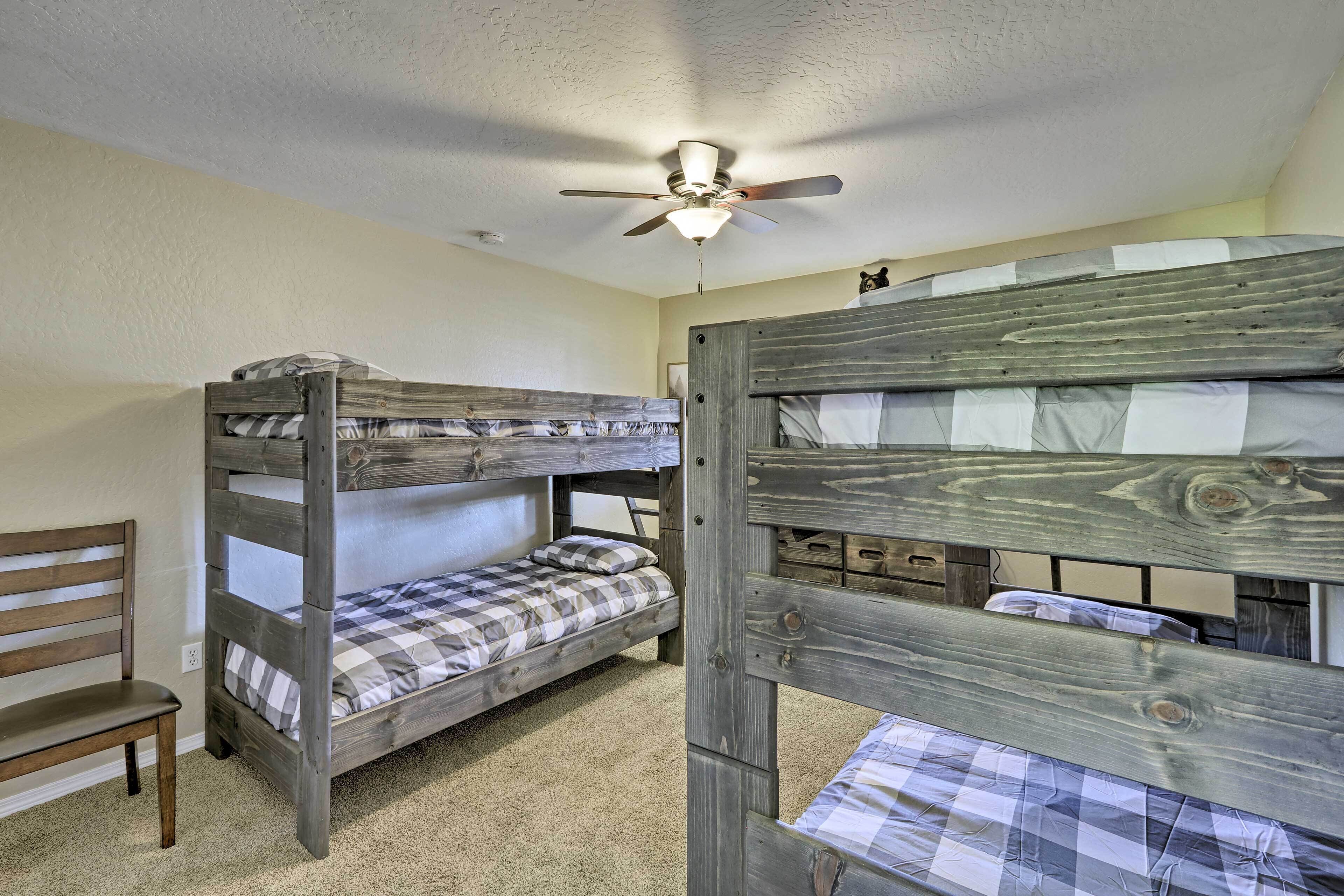 Ein Schlafzimmer mit Etagenbetten, Deckenventilator, Teppichboden und einer hölzernen Sitzbank.