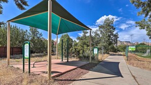 A park with a shaded area, exercise equipment, and informational signs.