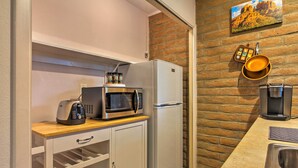 A compact kitchen with a stainless steel refrigerator, a microwave, and a toaster on a wooden countertop.