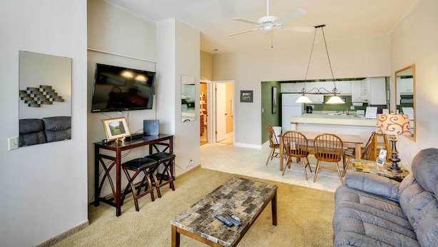 A living room with a TV, wooden furniture, a ceiling fan, and a kitchen area with a dining table and chairs. - Crossville Golfer's Haven: 5 On-site Courses! (Crossville)