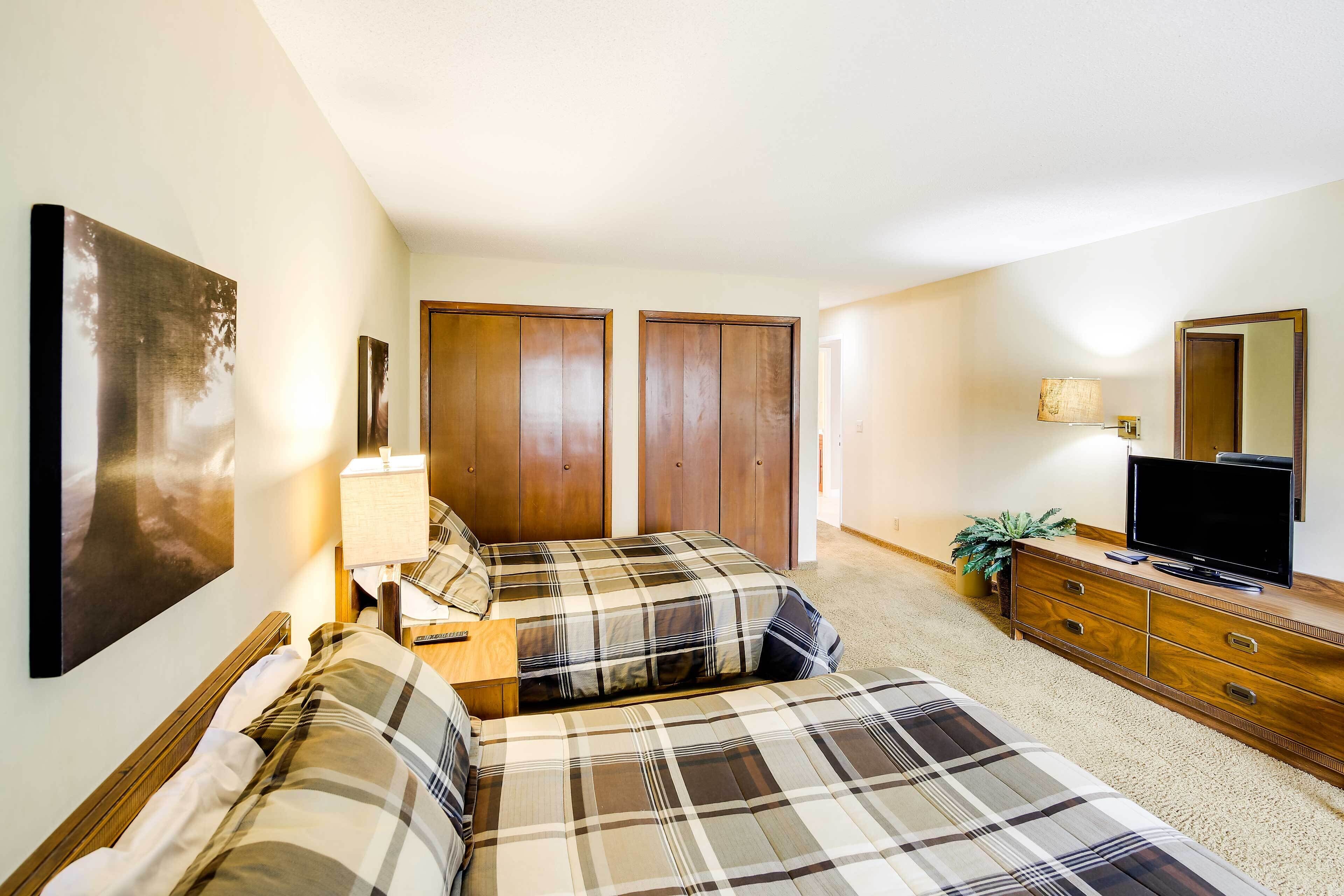 A bedroom with two beds, a dresser, a TV, and a large mirror.
