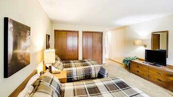 A bedroom with two beds, a dresser, a TV, and a large mirror.