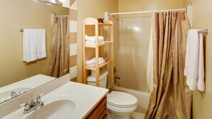 A bathroom with a white sink, mirror, and toilet. There is a shower curtain and a towel rack with towels. - Crossville Golfer's Haven: 5 On-site Courses! (Crossville)