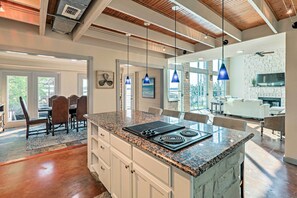 Une cuisine moderne dotée de plans de travail en granit, d’une cuisinière intégrée et de luminaires suspendus.