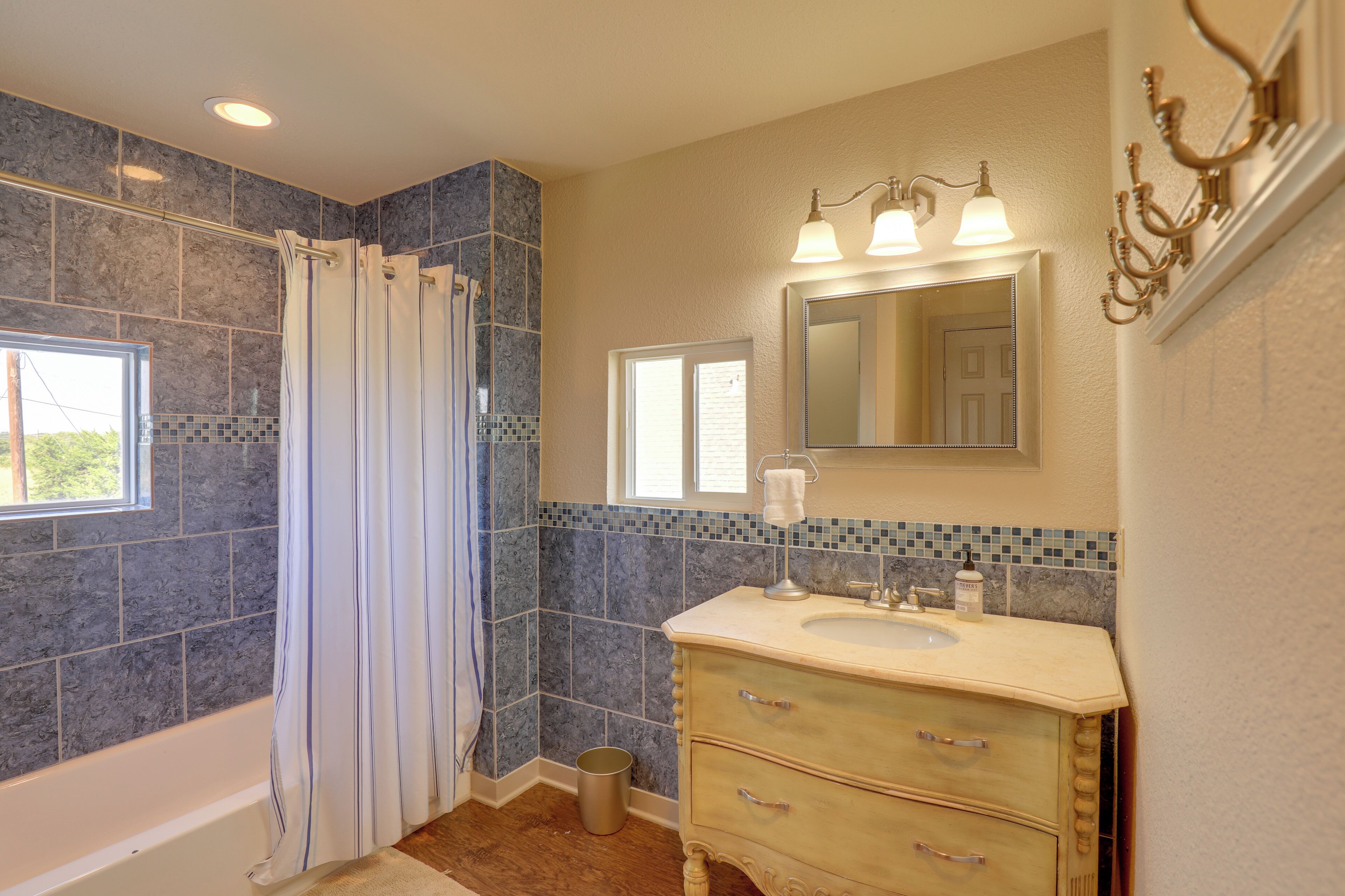 A bathroom with a bathtub, a vanity with a sink, a mirror, and a shower curtain.