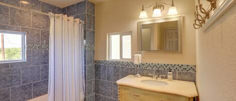 A bathroom with a bathtub, a vanity with a sink, a mirror, and a shower curtain.