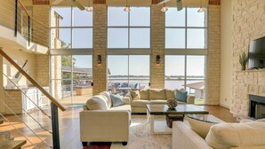A spacious living room with large windows, a fireplace, and a staircase leading to an upper level. - Waterfront Granbury House w/ Deck & Private Dock! (Granbury)