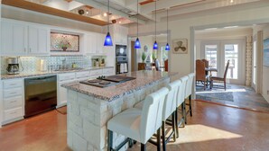 A spacious kitchen with a large island, white cabinetry, and blue pendant lights. - Waterfront Granbury House w/ Deck & Private Dock! (Granbury)