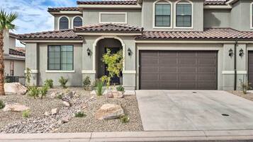 A two-story house with a tiled roof, a garage, and a landscaped front yard with rocks and plants.
