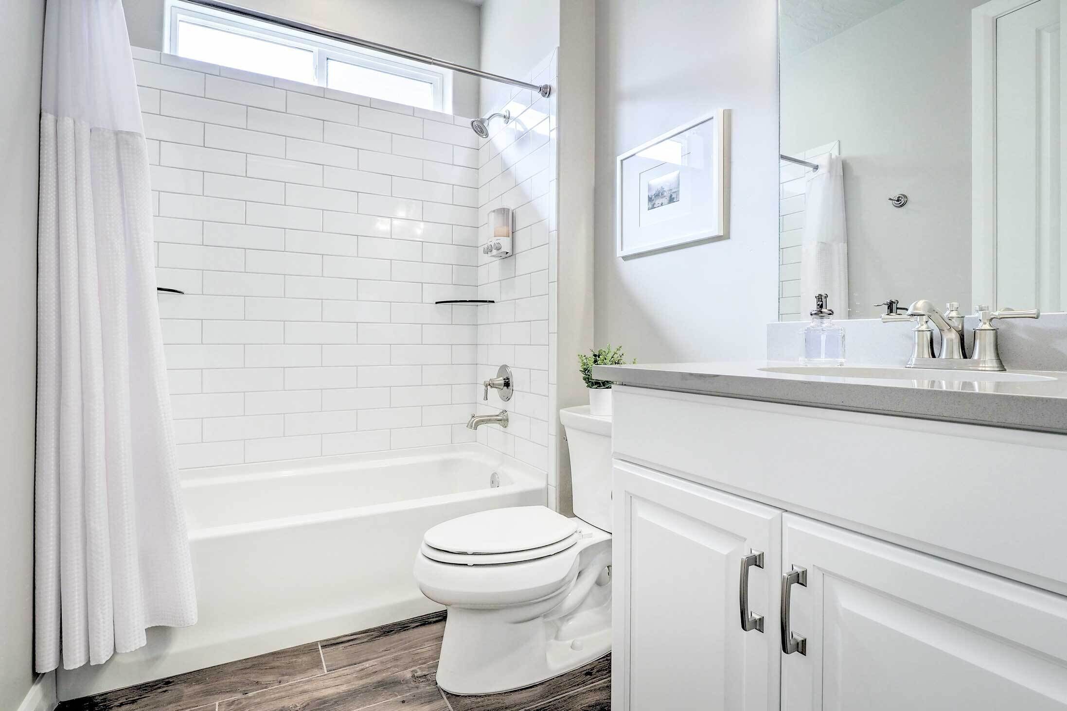 A modern bathroom with a white bathtub, toilet, and vanity.