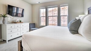 A bedroom with a large bed, a dresser, a TV, and a window with a view of a rocky landscape. - Lazy River, Arcade & Pickleball in Washington! (Washington)