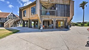 A wooden building with a balcony, outdoor seating, and a palm tree.
