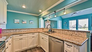 A kitchen with white cabinets, granite countertops, and a dishwasher.