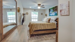 A bedroom with a large bed, a ceiling fan, a large mirror, and artwork on the walls. - Lake Conroe Vacation Rental 1/2 Mi to Boat Launch! (Willis)