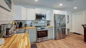 A modern kitchen with white cabinets, stainless steel appliances, and a wooden countertop. - Lake Conroe Vacation Rental 1/2 Mi to Boat Launch! (Willis)