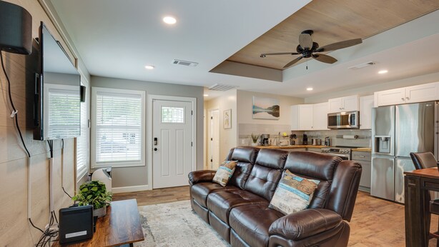 A modern kitchen with stainless steel appliances, a dining area with a wooden table, and a leather sofa with decorative pillows. - Lake Conroe Vacation Rental 1/2 Mi to Boat Launch! (Willis)