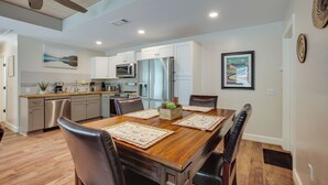 A modern kitchen with white cabinets, stainless steel appliances, and a dining area with a wooden table and leather chairs. - Lake Conroe Vacation Rental 1/2 Mi to Boat Launch! (Willis)