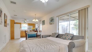 Un dormitorio amplio con una cama grande, un sofá gris y vistas a la cocina y al balcón.