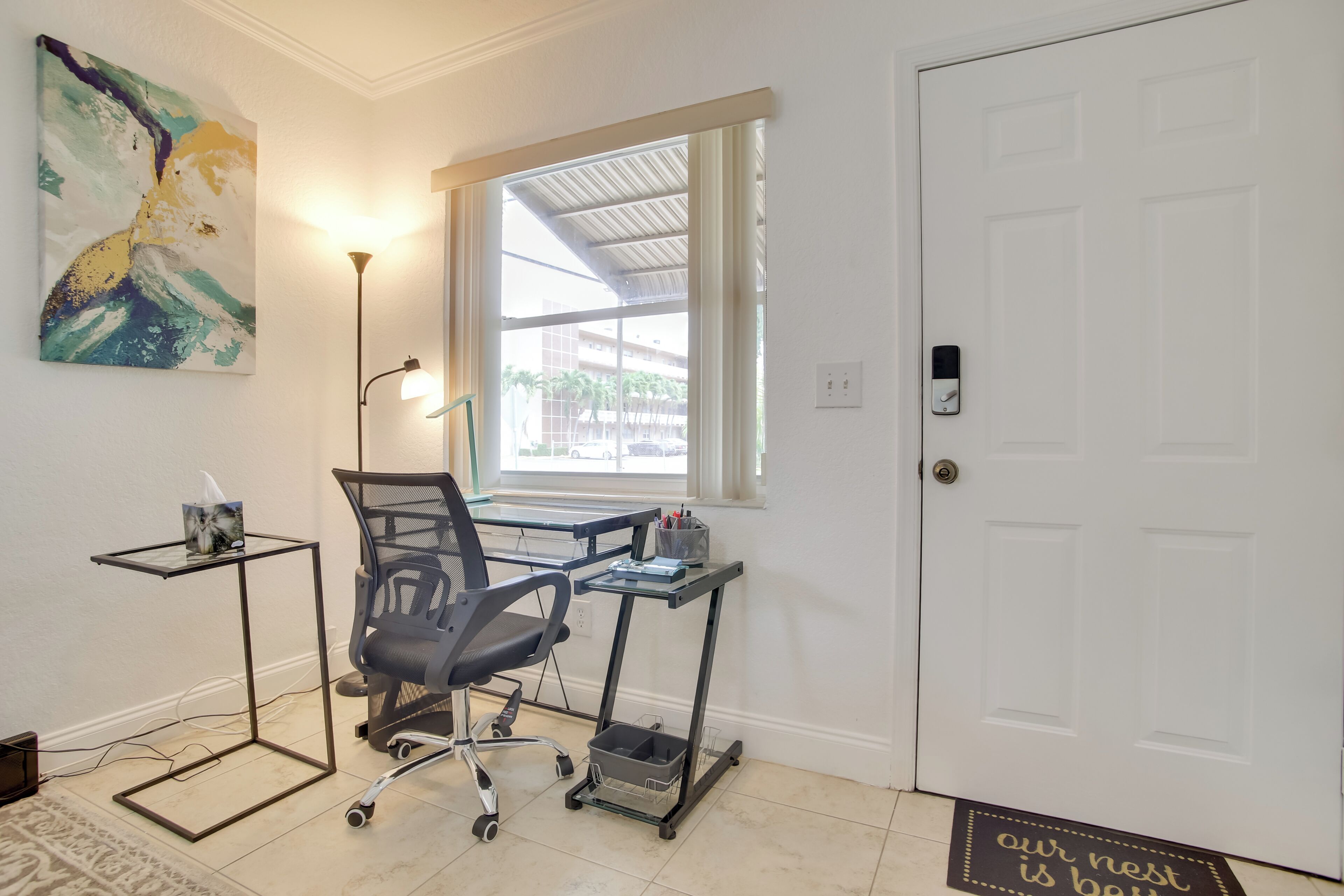 A room with a desk, chair, and a window with a view of buildings.
