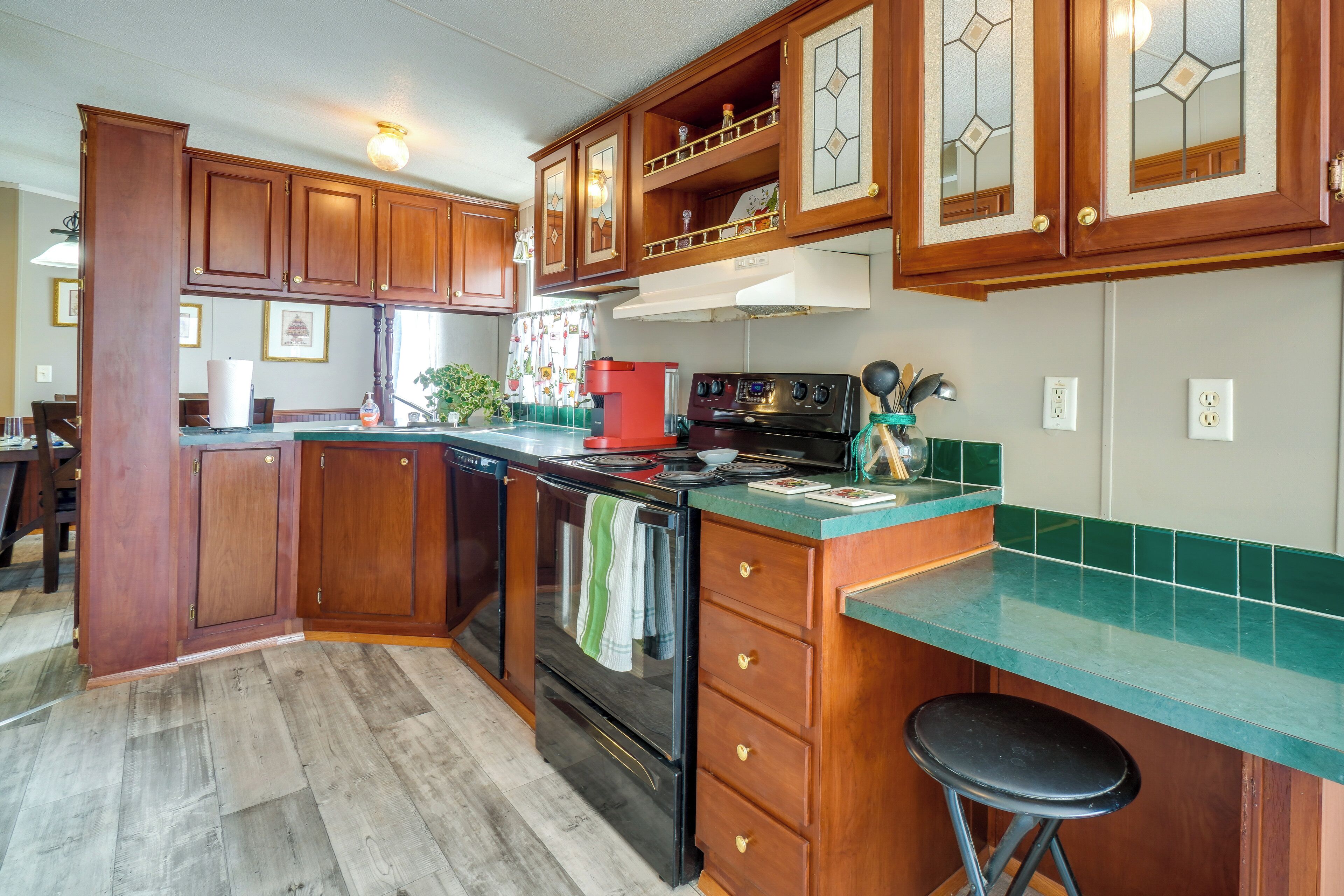A kitchen with wooden cabinets, a stove, and a green countertop.