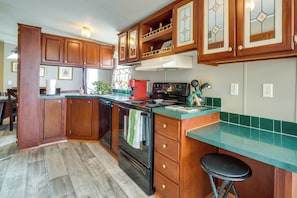 A kitchen with wooden cabinets, a stove, and a green countertop.