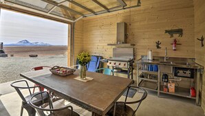Eine rustikale Küche mit großem Fenster, Holzwänden, einem Gasherd und einem Spülbecken.