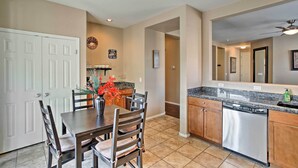 A modern kitchen with a dining area, featuring a granite countertop, stainless steel dishwasher, and wooden cabinets. - Dog-friendly Arizona Retreat w/ Patio & Grill! (Gilbert)