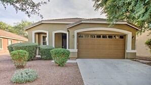 A single-story house with a garage, a front door, and two small bushes. - Dog-friendly Arizona Retreat w/ Patio & Grill! (Gilbert)