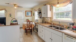 A kitchen with a dining table, chairs, a microwave, a sink, and cabinets.