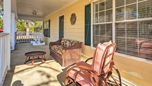 A covered porch with wicker furniture, a chair, and a small table.