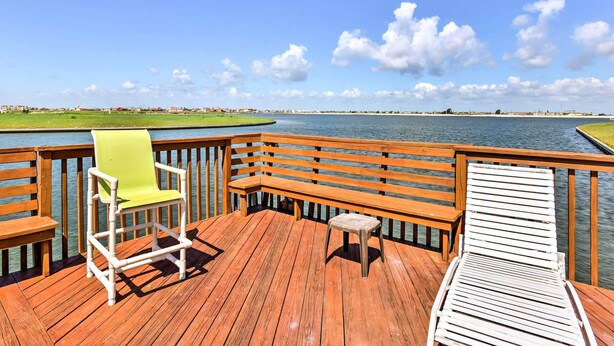 Une terrasse en bois avec un banc, une chaise et un petit tabouret.