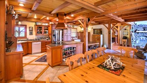 A spacious kitchen with wooden beams, a central island, and a dining area with wooden chairs. - Stunning Silesia Home: Furnished Deck + River View (Joliet)