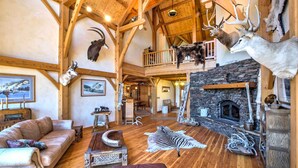 A rustic interior with a stone fireplace, wooden beams, and mounted animal heads. - Stunning Silesia Home: Furnished Deck + River View (Joliet)