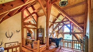 A wooden interior with high ceilings, a staircase, and a large animal statue. - Stunning Silesia Home: Furnished Deck + River View (Joliet)