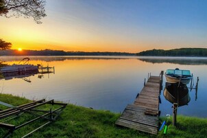 Un lago tranquilo al atardecer con un muelle de madera que se adentra en el agua.