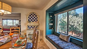 A dining area with a wooden table set for four, a checkered wall, and a view of trees through a large window. - Bike, Hike & Unwind: Tranquil Payson Getaway! (Payson)
