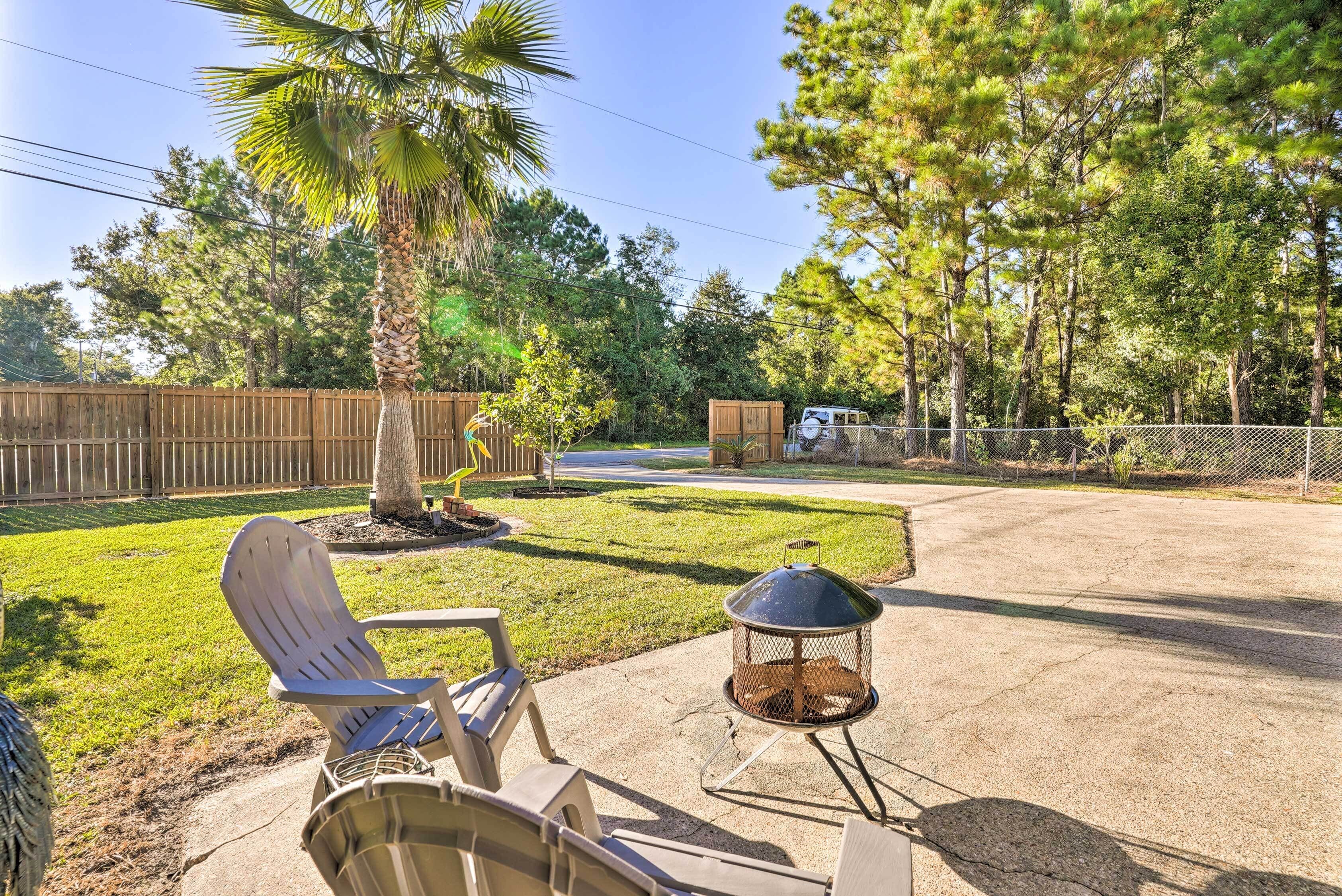 A backyard with a patio area, a fire pit, and a wooden fence.