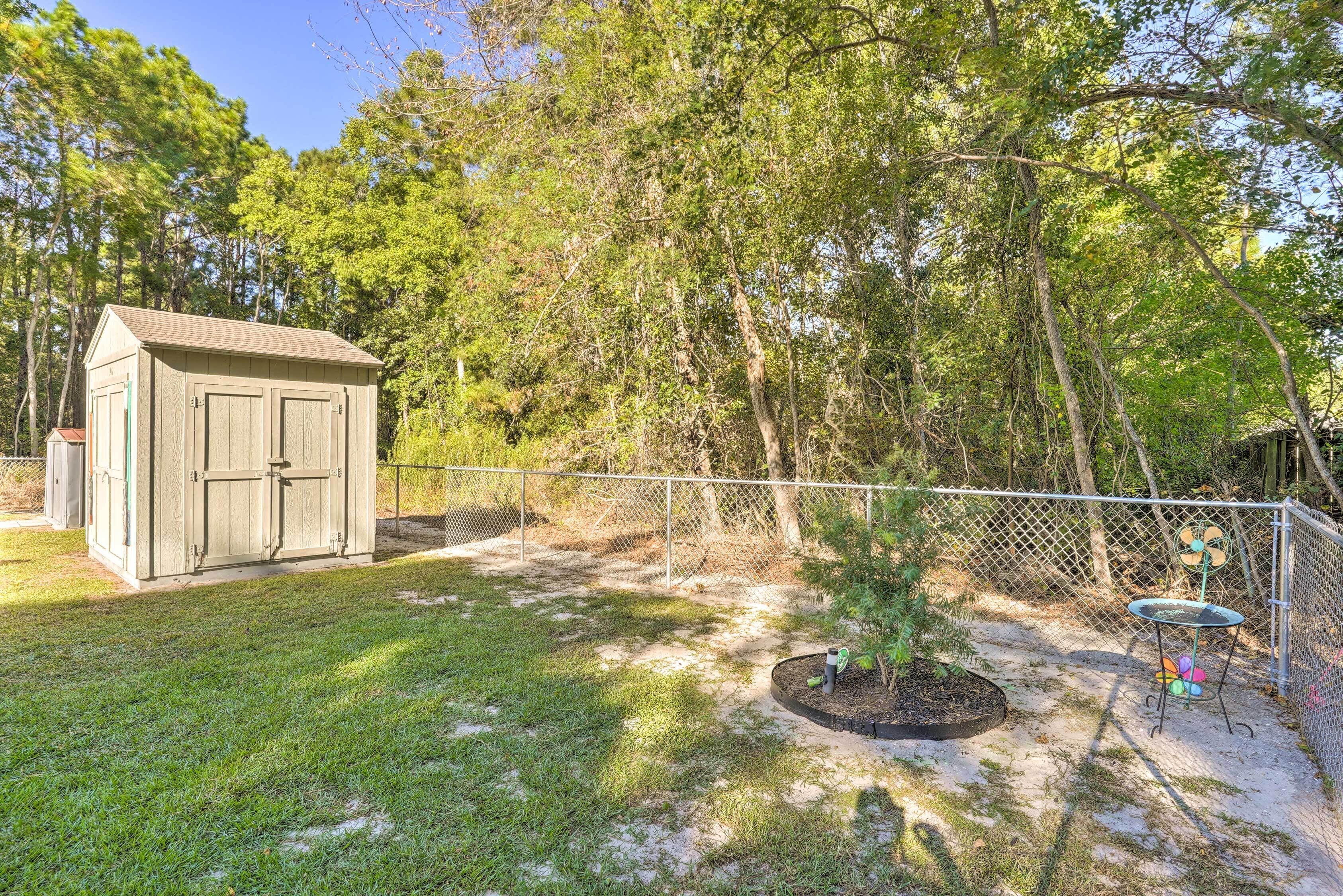 A fenced backyard with a shed, a small tree, and a metal table with chairs.