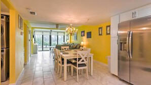 A modern kitchen with a dining area, stainless steel appliances, and a bright yellow wall. - Cheery Condo With Pool Access: 3 Miles to Beach! (Fort Myers)